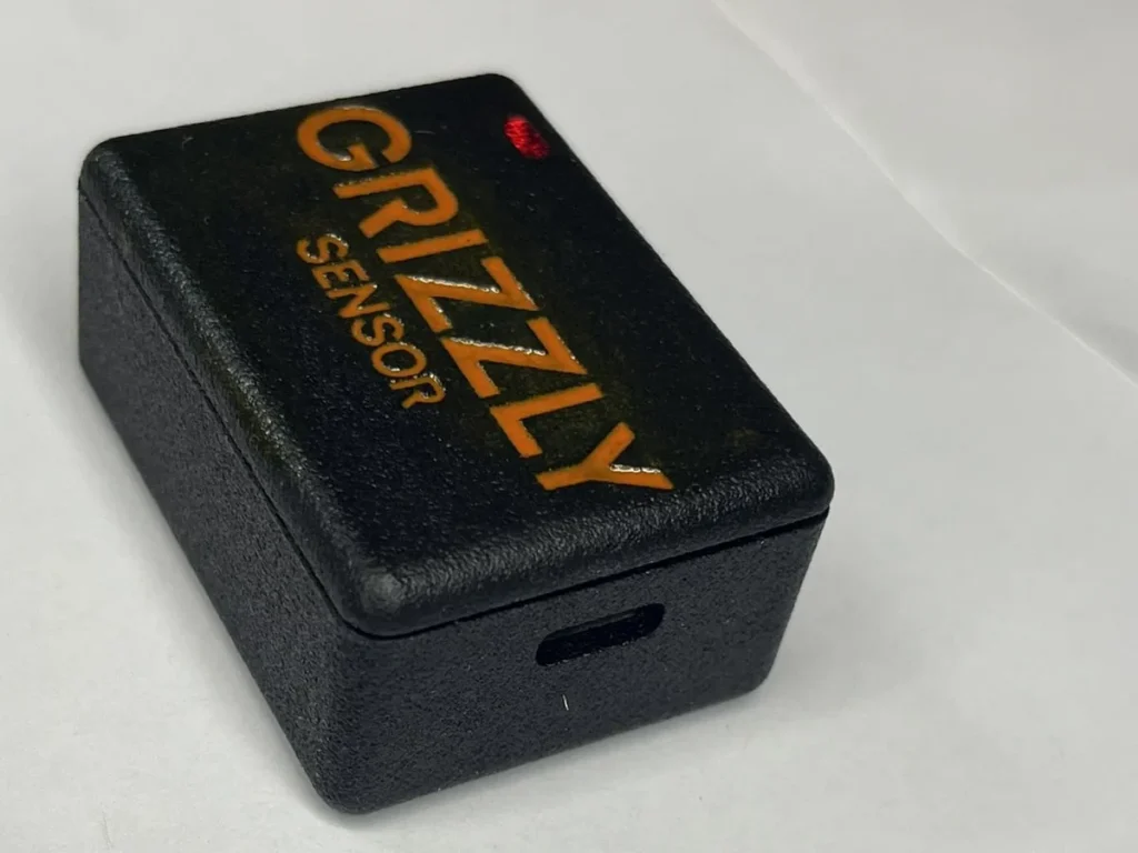 Grizzly Sensor: gabinete preto texturizado com a marca GRIZZLY SENSOR em laranja e LED indicador